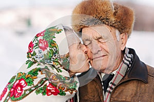 Portrait of happy senior couple. Elderly woman kiss her husband in weighty. old couple walking in the park in winter