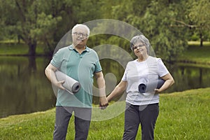 Portrait of happy senior couple with exercise mats after yoga practice in nature