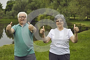 Portrait of happy senior couple giving thumbs up after doing sports exercise in nature