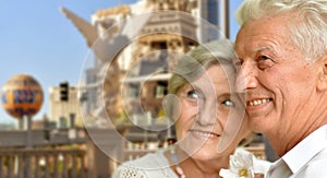 Portrait of happy senior couple posing against blurred cityscape background