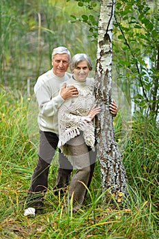 Portrait of happy senior couple posing in autumn forest