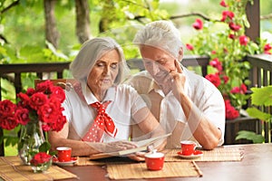 Portrait of happy senior couple reading book while drinking coffee