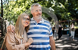 Portrait of happy senior couple standing outdoors in city or town park.