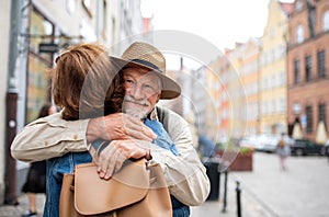 Portrait of happy senior couple tourists hugging outdoors in historic town