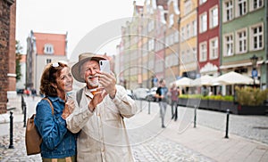 Portrait of happy senior couple tourists making selfie outdoors in historic town