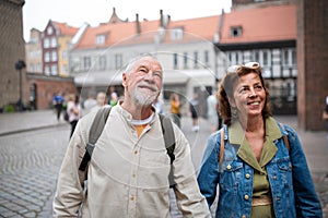 Portrait of happy senior couple tourists outdoors in historic town