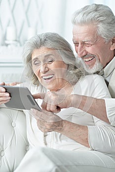 Portrait of happy senior couple using tablet at home