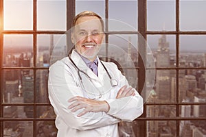 Portrait of happy senior doctor with folded arms.