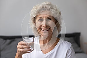 Portrait happy senior elderly woman holding glass of water.