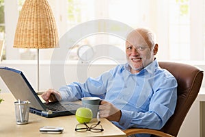 Portrait of happy senior man with computer