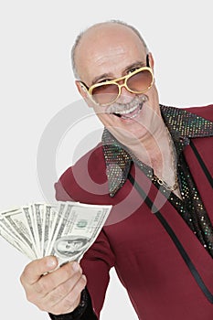 Portrait of happy senior man showing US banknotes against gray background