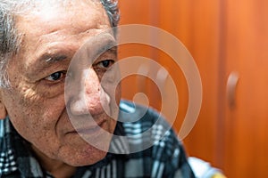 Portrait of happy senior man smiling at home. Old man relaxing on sofa. Portrait of elderly man enjoying retirement.