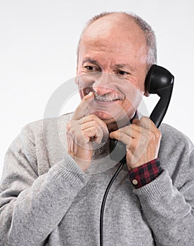 Portrait of happy senior man talking on old landline phone