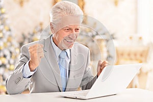 Portrait of happy senior man using laptop at home