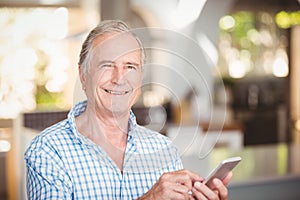 Portrait of happy senior man using mobile phone