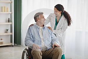Portrait of happy senior man in wheelchair and his female nurse at retirement home