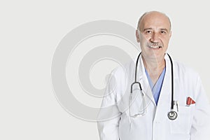 Portrait of happy senior medical practitioner over gray background