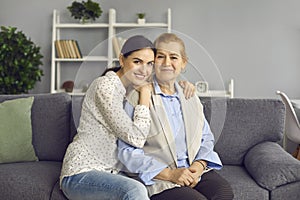 Portrait of happy senior mother together with her grown-up daughter sitting on sofa