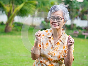 Portrait of happy senior woman clenching fists excited for success with arms raised celebrating victory smiling while standing