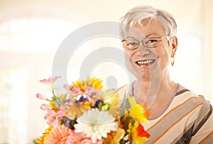 Portrait of happy senior woman with flowers