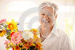 Portrait of happy senior woman holding flowers