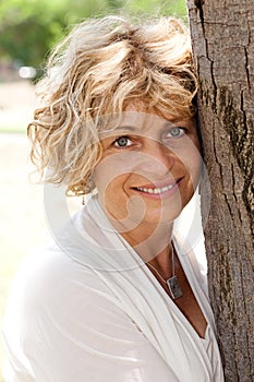 Portrait of a happy senior woman holding tree