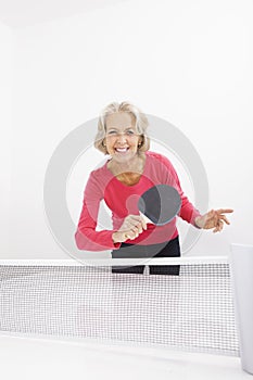 Portrait of happy senior woman playing table tennis