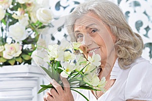 Portrait of happy senior woman posing with flowers