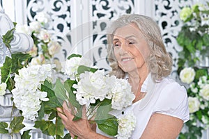 Portrait of happy senior woman posing with flowers