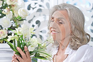 Portrait of happy senior woman posing with flowers