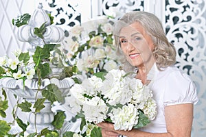 Portrait of happy senior woman posing with flowers