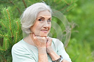 Portrait of happy senior woman posing at forest