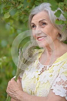 Portrait of happy senior woman posing at forest