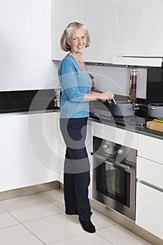 Portrait of happy senior woman preparing food in kitchen