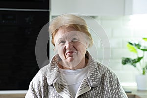 Portrait of happy senior woman sitting in kitchen at home, copy space for text