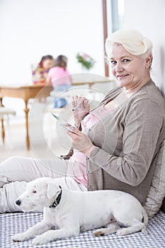 Portrait of happy senior woman using digital tablet by dog at home