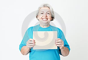 Portrait of happy senior woman wearing blue tshirt with blank advertising board or copy space