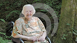 Portrait of happy senior woman in a wheelchair in the forest