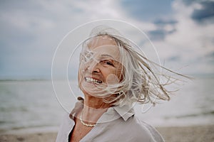Portrait of happy senior woman with wind in hair, near sea.