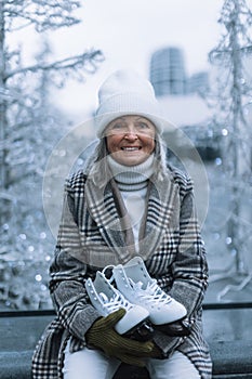 Portrait of happy senior woman in winter at outdoor ice skating rink.