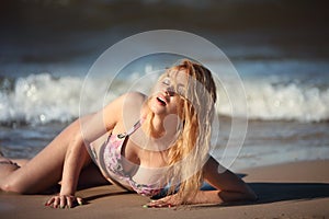 Portrait of happy girl in pink bikini posing against sea