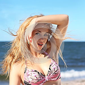 Portrait of happy girl in pink bikini posing against sea