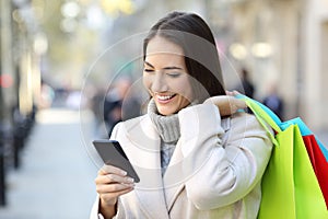 Shopper using a smart phone holding shopping bags photo