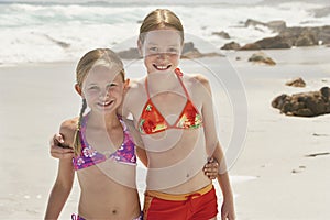 Portrait Of Happy Sisters Standing On Beach