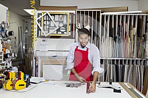 Portrait of a happy skilled worker measuring with meter stick in workshop photo