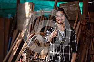 Portrait of happy smile young carpenter caucasian man worker thumbs up with circular saw in factor.