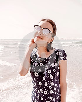 Portrait of happy smile young girl in sunglasses stands near the sea