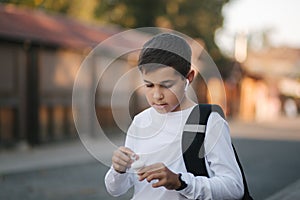 Portrait of happy smiled teenage boy in white sweatshirt with backpack outside