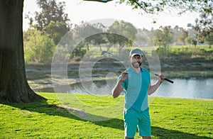 Portrait of happy smilin golfer hitting golf shot with club on course.