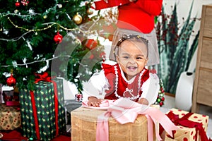 Portrait of happy smiling adorable African American little girl child standing in living room with many gift boxes presents under